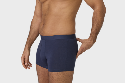 Man wearing navy blue boxer briefs on a white background