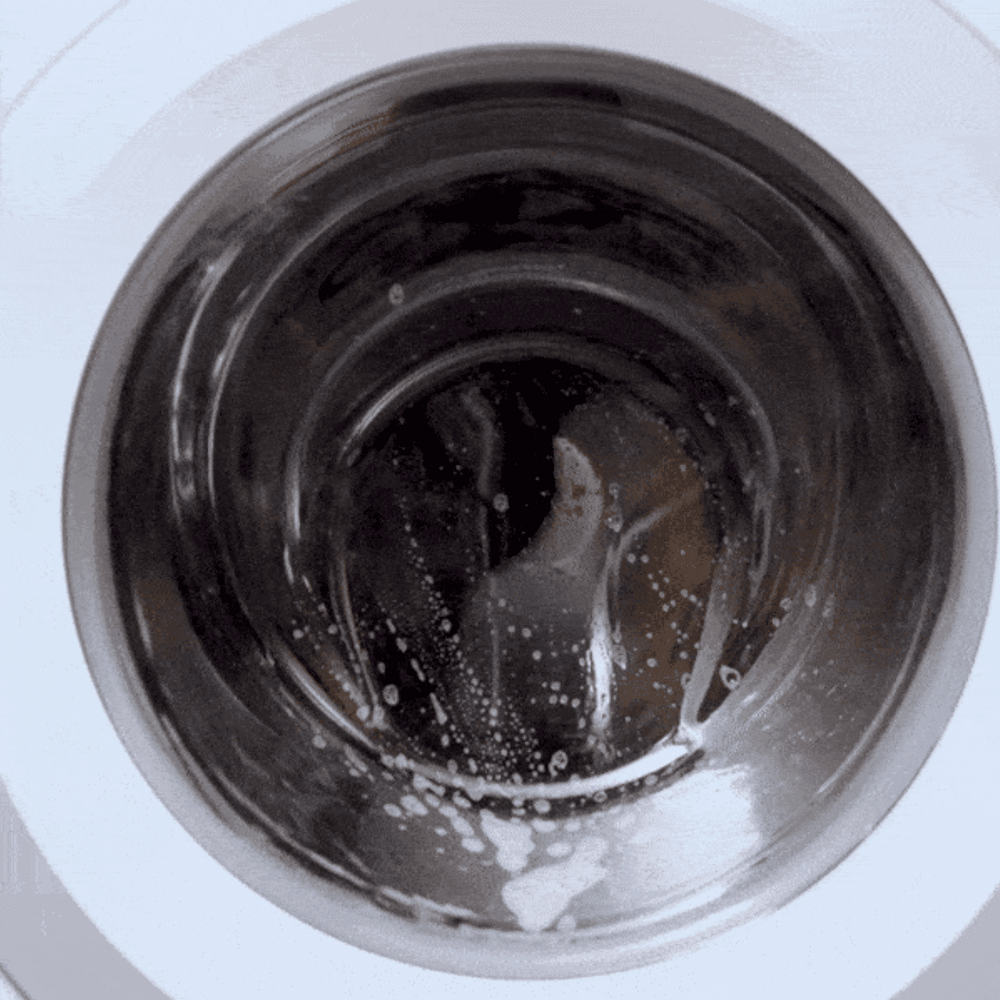 Washing machine drum spinning with soapy water inside, viewed from the front perspective.