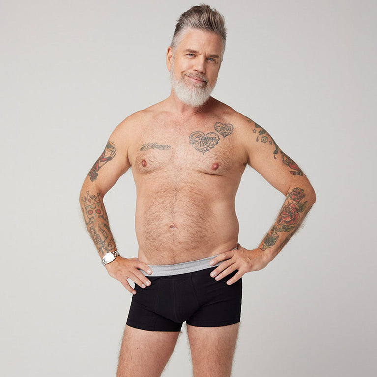 TENA Men Protective Boxers Light worn by a tattooed man, showcasing their discreet design and comfortable fit, ideal for light incontinence protection.