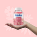 Hand holding Issviva “Hair Skin &amp; Nails” gummies jar from the Stylish Beauty Bumper Bundle, featuring a pink floral label and 60 red/pink gummies for hair, skin, nails health.