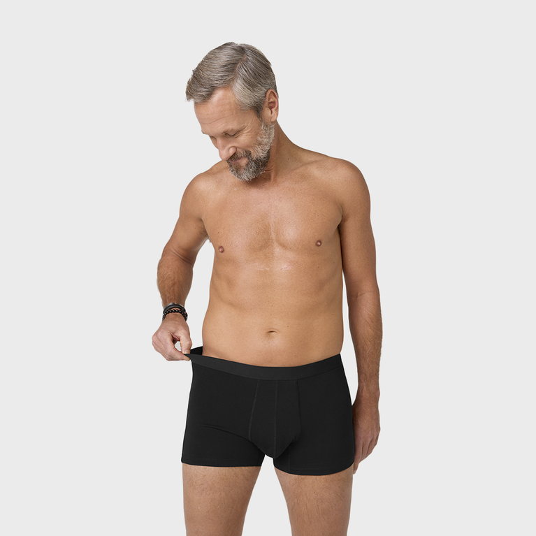 Man wearing NEW TENA Men Protective Boxers Light, showcasing the fit and design of washable incontinence boxers made from organic cotton with an elastic waistband.