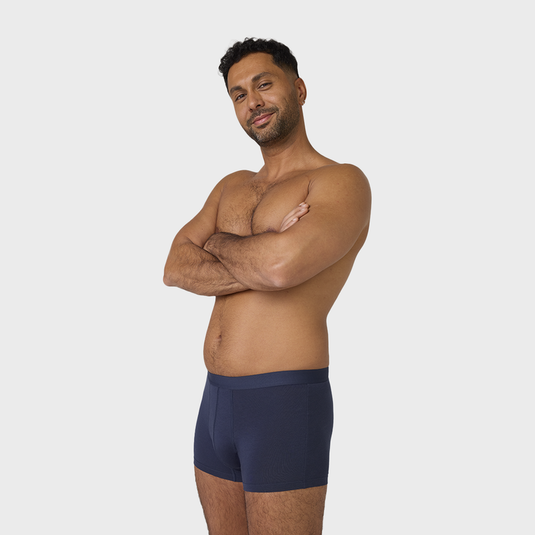 Man wearing NEW TENA Men Protective Boxers Light, arms crossed; showcases soft, comfortable fit, offering discreet incontinence protection and washable for repeated use.