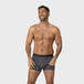 Man wearing NEW TENA Men Protective Boxers and a silver chain necklace smiles, showcasing the boxers&