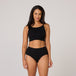 Woman wearing TENA Organic Cotton Underwear, black ribbed crop top and high-waist briefs, showcasing comfort and fit for light bladder leaks.