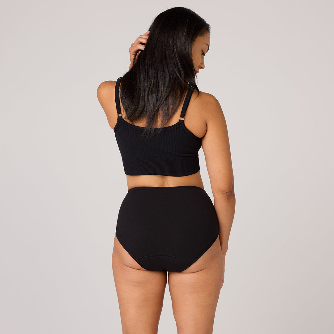 Model showcasing TENA 3 Pack Organic Cotton Underwear, featuring a black ribbed crop top and high-waisted briefs, designed for comfort and light leak protection.