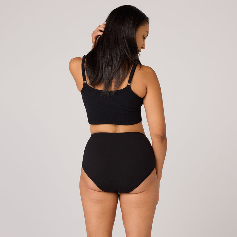 Model showcasing TENA 3 Pack Organic Cotton Underwear, featuring a black ribbed crop top and high-waisted briefs, designed for comfort and light leak protection.
