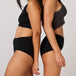 Two women model TENA 3 Pack Organic Cotton Underwear, showcasing the black ribbed crop tops and high-waisted design for stylish, comfortable incontinence protection.